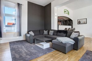 En moderne stue med en grå modulsofa, et hvidt sofabord og et gråt tæppe.