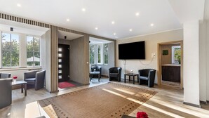 A modern living room with a large rug, seating area, and a flat-screen TV.