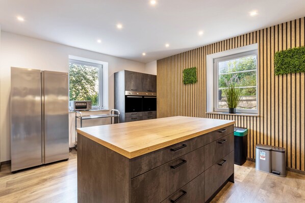 Una cocina moderna con una isla central, electrodomésticos de acero inoxidable y una pared jardín vertical.