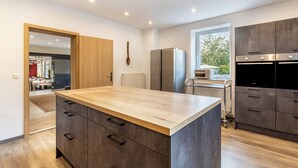 Een moderne keuken met een houten aanrechtblad, donkere kastjes en inbouwapparatuur.