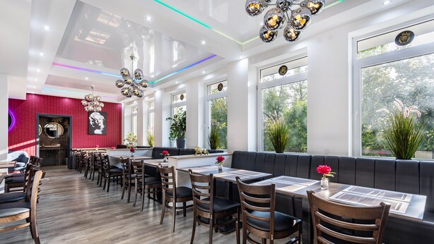 Een restaurant met een lange toonbank, meerdere tafels en zitjes.