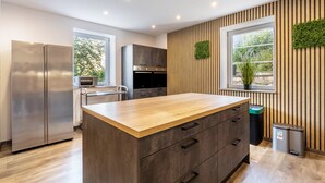 Een moderne keuken met een houten kookeiland, roestvrijstalen apparatuur en een verticale groene wand.