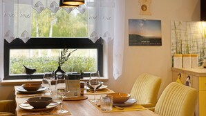 A dining table set with bowls, glasses, and a menu, with a window view and a clock on the wall. - Holiday Home 'Mond am See' with Lake View, Private Terrace and Wi-Fi (Stechow-Ferchesar)
