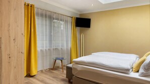 A bedroom with a bed, a TV mounted on the wall, and a wooden wardrobe. - Holiday Home 'Mond am See' with Lake View, Private Terrace and Wi-Fi (Stechow-Ferchesar)