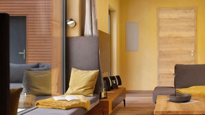 A modern room with a bed, a sofa, a small table, and a door. - Holiday Home 'Mond am See' with Lake View, Private Terrace and Wi-Fi (Stechow-Ferchesar)