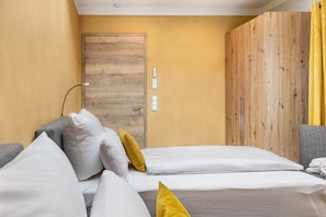 Ein Zimmer mit einem Bett, einer Holztür und einer Wand mit Lichtschalter.