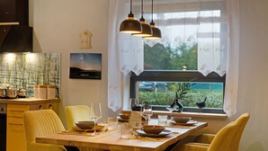 Un comedor con una mesa de madera, sillas amarillas y lámparas colgantes.