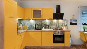 Una cocina moderna con gabinetes amarillos, horno integrado y salpicadero con líneas verticales.