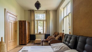 A hotel room with a large bed, two armchairs, a wooden wardrobe, and a window with curtains. - Africana by Grand Apartments (Sopot)