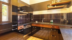 A modern kitchen with dark cabinetry, a stainless steel range hood, and a built-in oven. - Africana by Grand Apartments (Sopot)