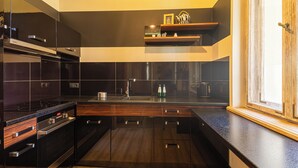 A modern kitchen with dark cabinetry, a stainless steel range, and a built-in oven. - Africana by Grand Apartments (Sopot)