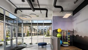 A modern gym with exercise equipment, a blue bench, and a view of a mountain landscape through large windows.