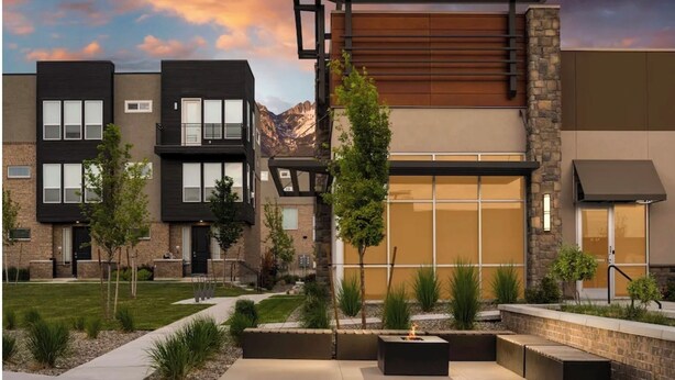 A modern residential building with a flat roof, large windows, and a stone facade.