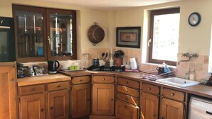 A kitchen with wooden cabinets, a stove, and a sink. - Countryside Home Sleeps 6 - Garden, Parking, Wifi (Landivy)