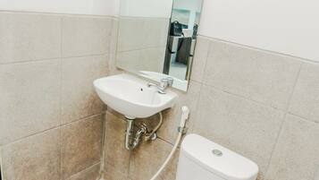 Une salle de bain avec un lavabo blanc, un miroir et des toilettes.