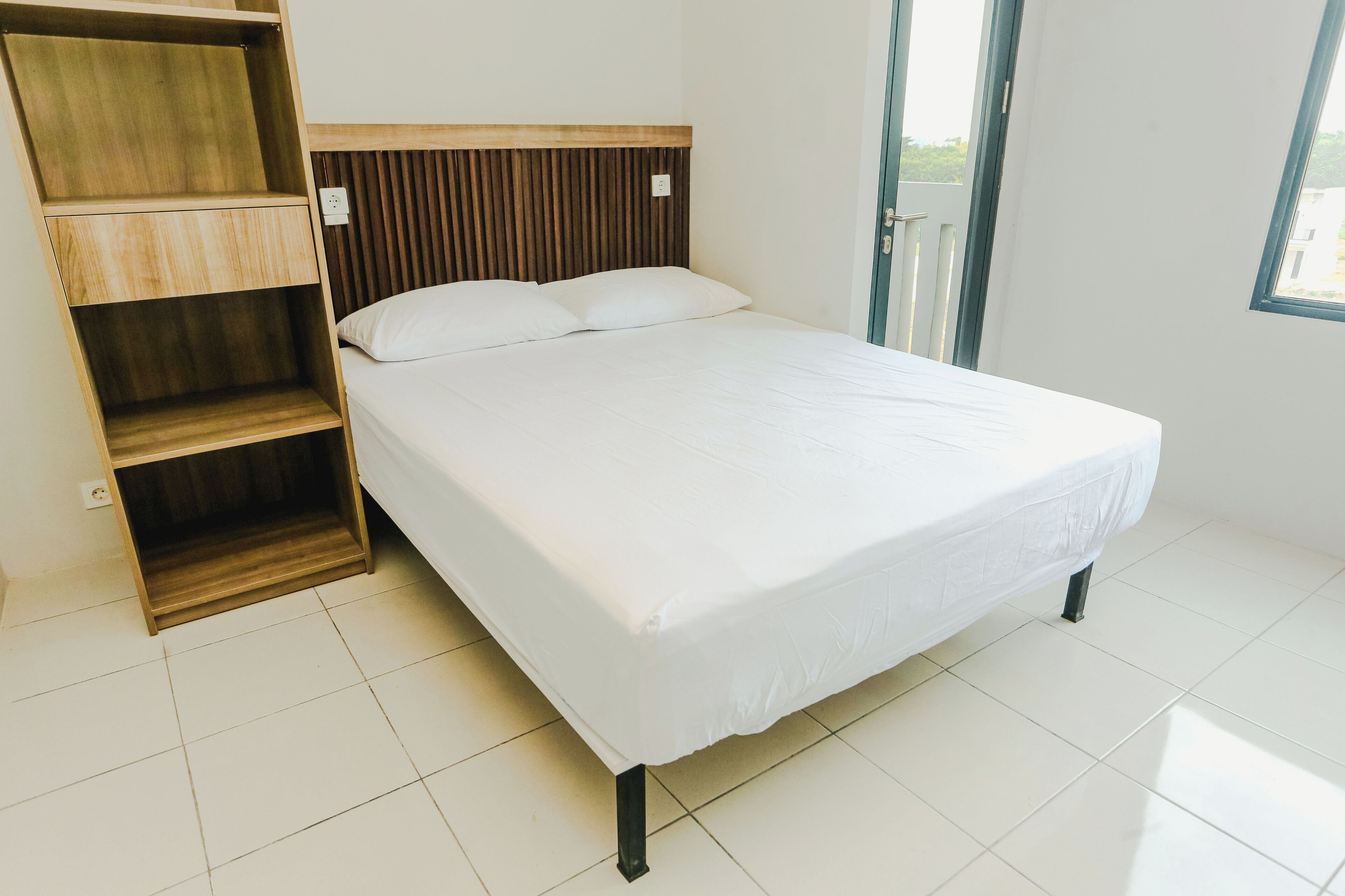 Un dormitorio con cama, estantería de madera y ventana.