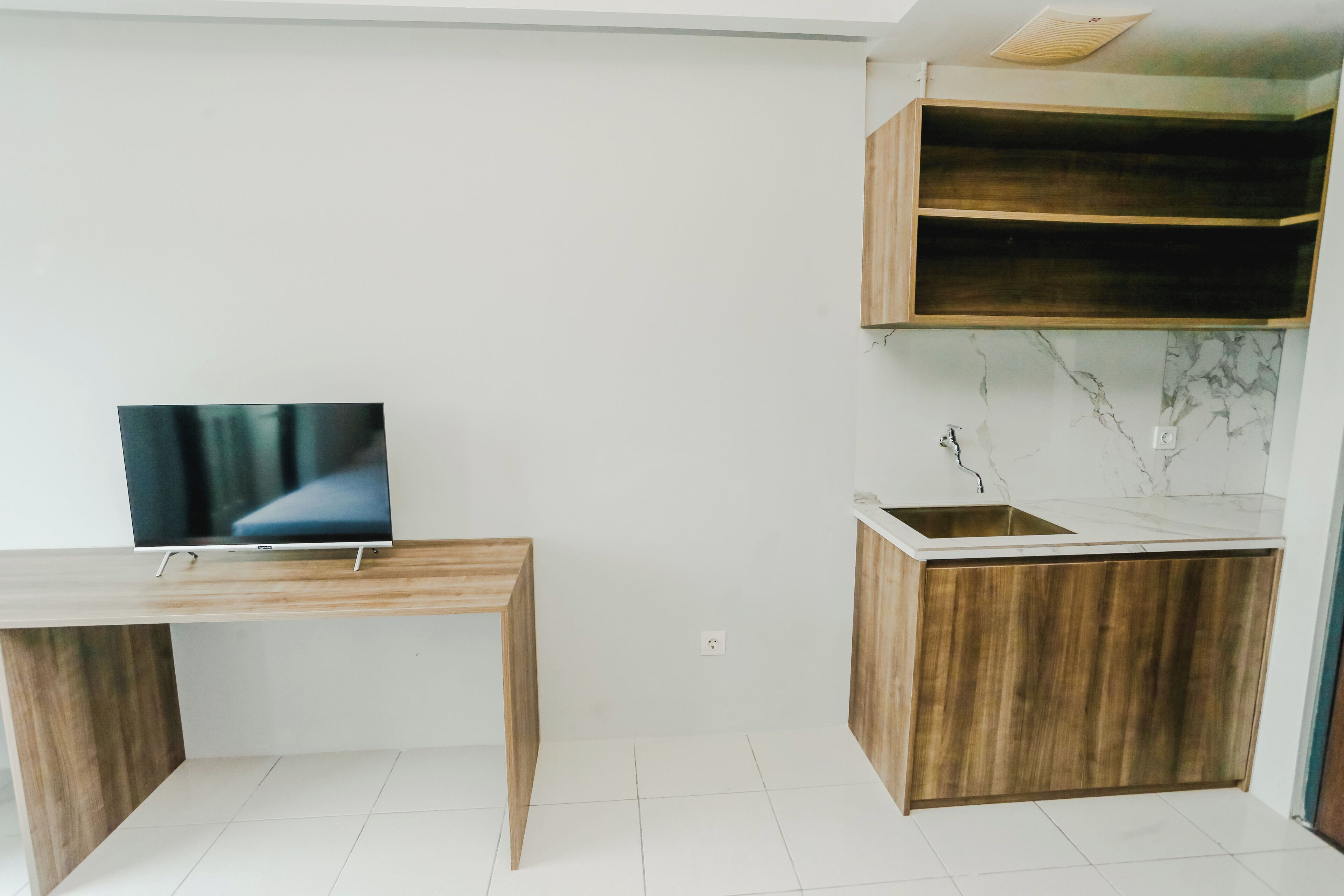 Una cocina moderna con encimera de madera, pileta integrada y un televisor sobre un mueble de madera.
