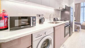 A modern kitchen with a microwave, coffee maker, and dishwasher. - Spacious Azizi Riviera Studio (Dubai)