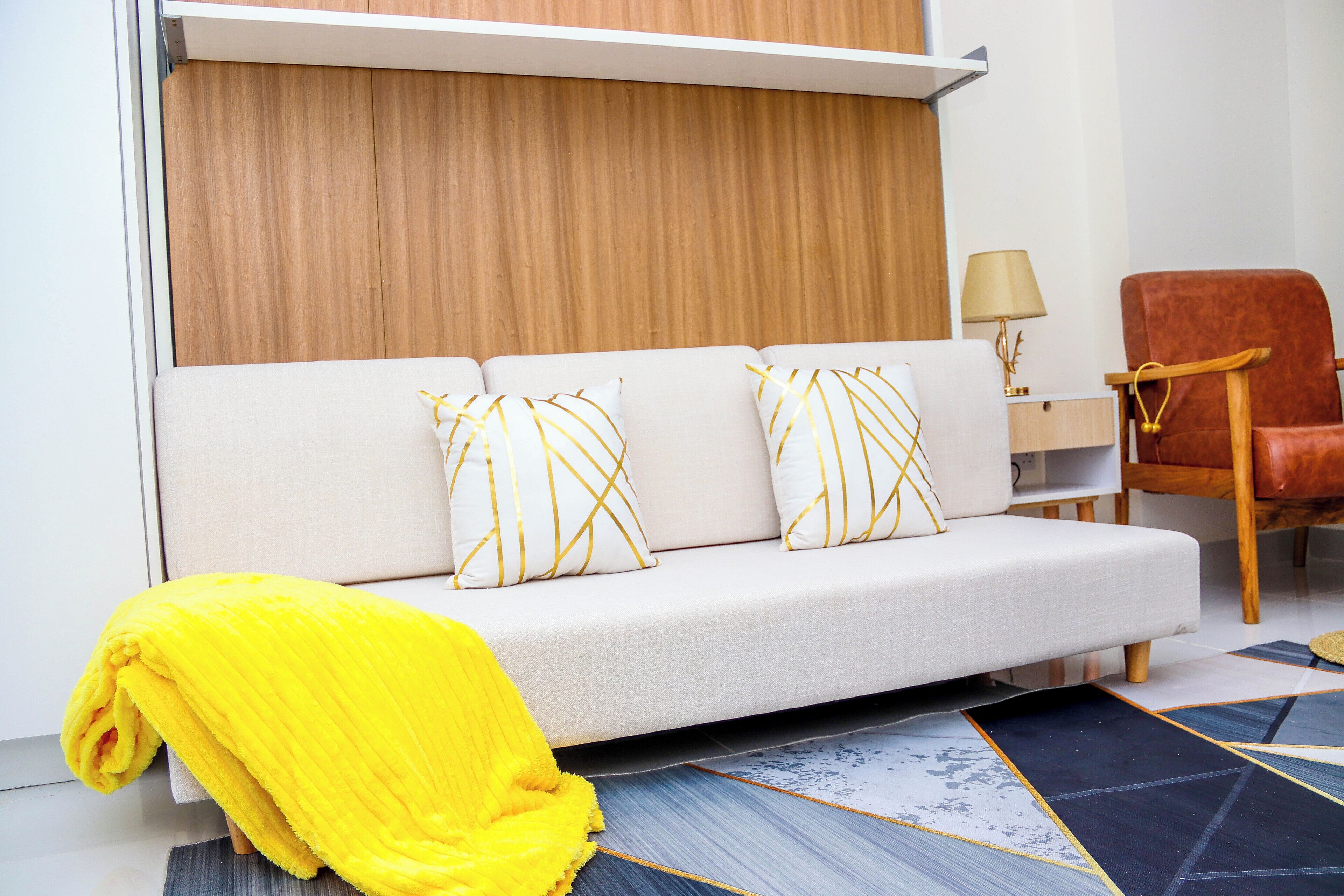 A modern living room with a sofa, a wooden panel wall, a lamp, and a chair.