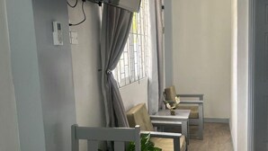 A living room with a sofa, a coffee table, and a TV mounted on the wall. - Lovely Studio Apartment in Soufriere from Claviers (Soufriere)