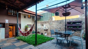 A patio area with a hammock, outdoor seating, a stone wall, and a sign indicating a fire alarm.