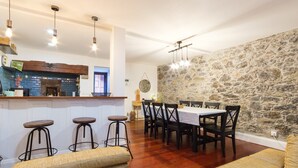 A dining area with a stone wall, wooden flooring, and a bar with stools.