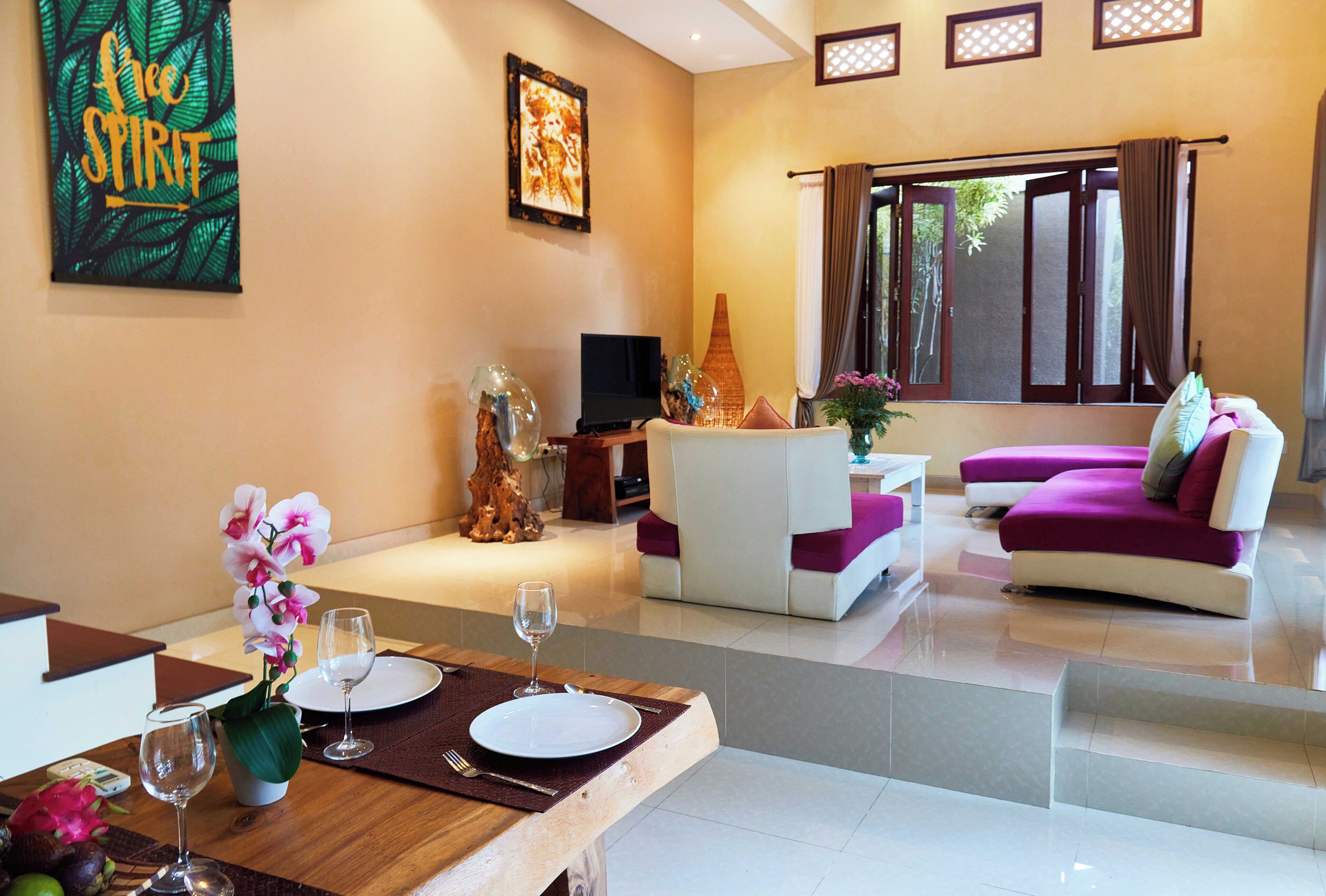 A modern hotel room with a dining area, a sofa, and a TV.