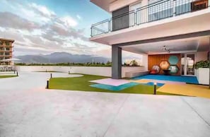 Um edifício moderno com telhado plano, varanda e área de piscina.