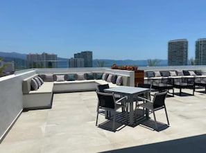 Uma área externa com espaço para sentar, incluindo uma mesa, cadeiras, um sofá e um armário de madeira.