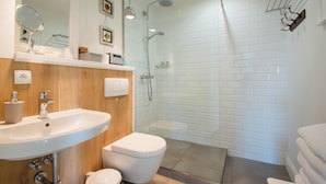 A modern bathroom with a white sink, toilet, and glass-enclosed shower. - Nautica by Grand Apartments (Sopot)