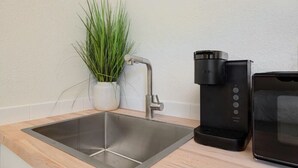 A kitchen with a stainless steel sink, a coffee maker, and a toaster.