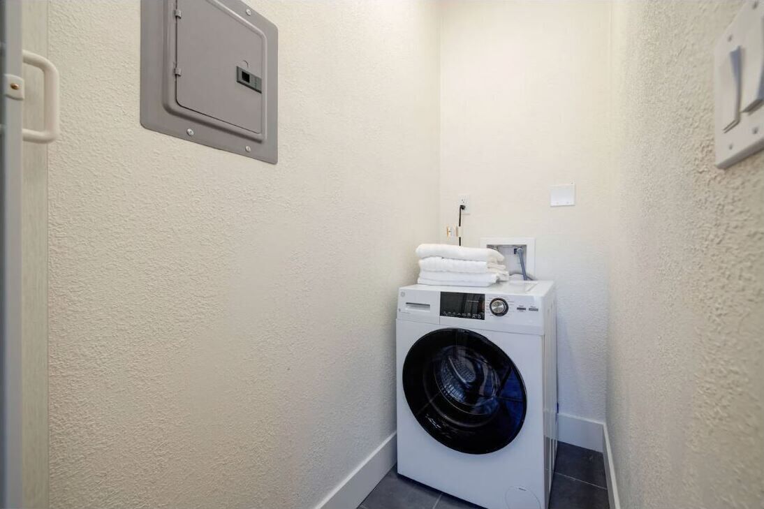 Une petite buanderie équipée d’un lave-linge à chargement frontal et de piles de serviettes.