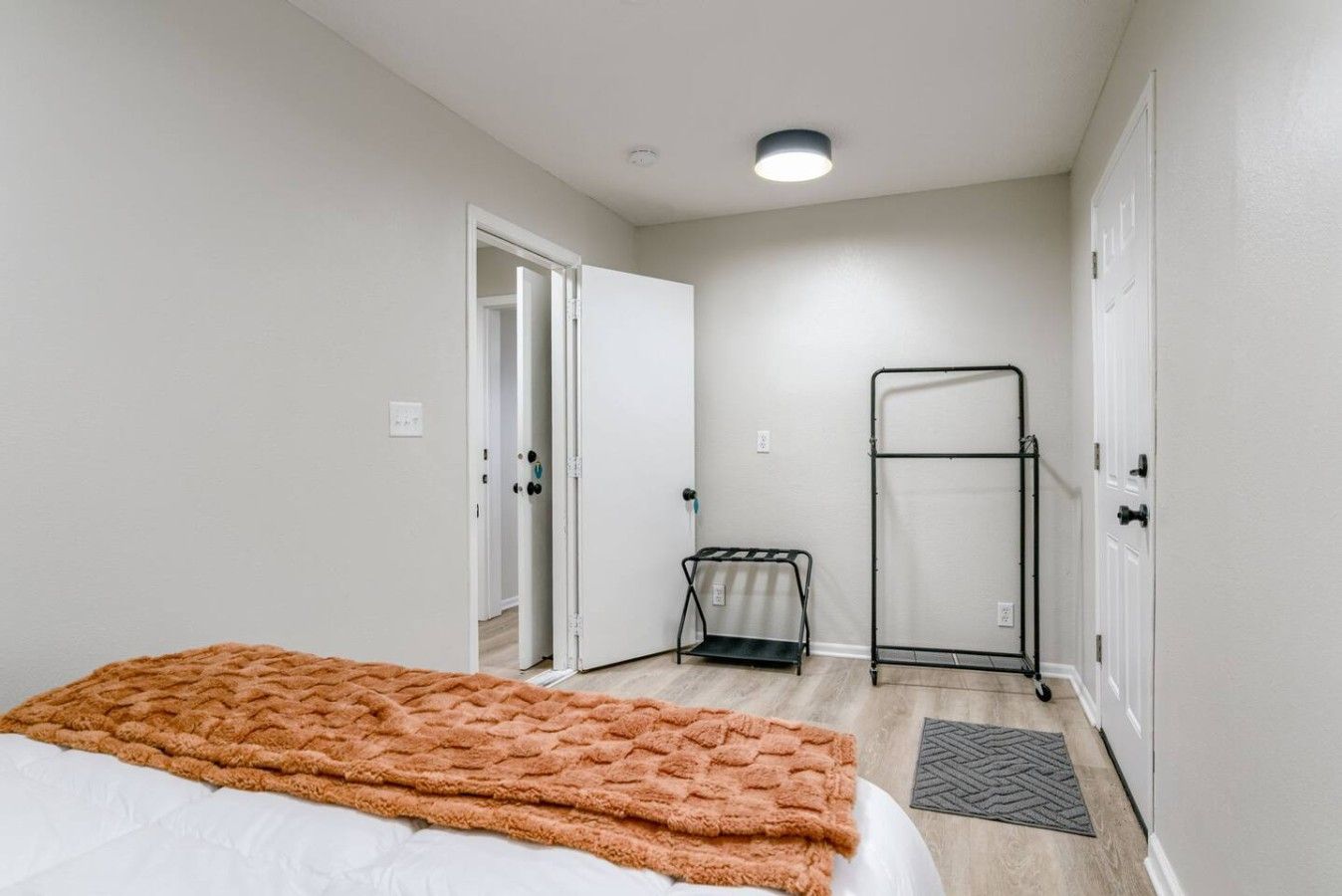 A bedroom with a bed, a radiator, a door, and a wall-mounted rack.