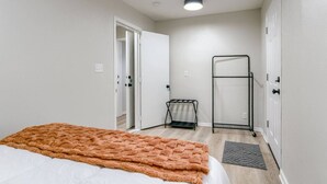 Ein Schlafzimmer mit einem Bett, einem Heizkörper, einer Tür und einem an der Wand befestigten Ablagefach.