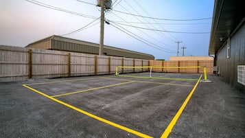 A parking lot with yellow lines marking spaces, a wooden fence, and a building with a metal roof.