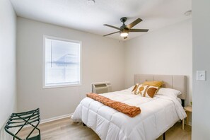 A bedroom with a bed, a ceiling fan, a window with blinds, and a chair.