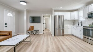 Eine moderne Küche mit weißen Schränken, einem Edelstahl-Kühlschrank und einem Essbereich mit einem Marmortisch.