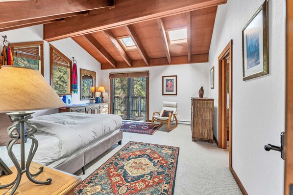 Une chambre à coucher comprenant un lit, une table de chevet, une lampe, une chaise, un tapis et une armoire en bois.