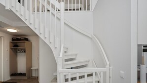 A white staircase with a handrail, leading to a landing with a shoe rack and a small table. - Leviraitti 4 a 4 by Interhome (Kittilä)