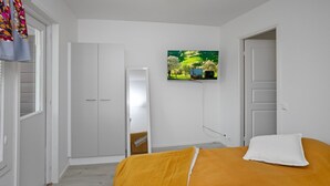 A bedroom with a bed, a TV mounted on the wall, and a wardrobe. - Leviraitti 4 a 4 by Interhome (Kittilä)