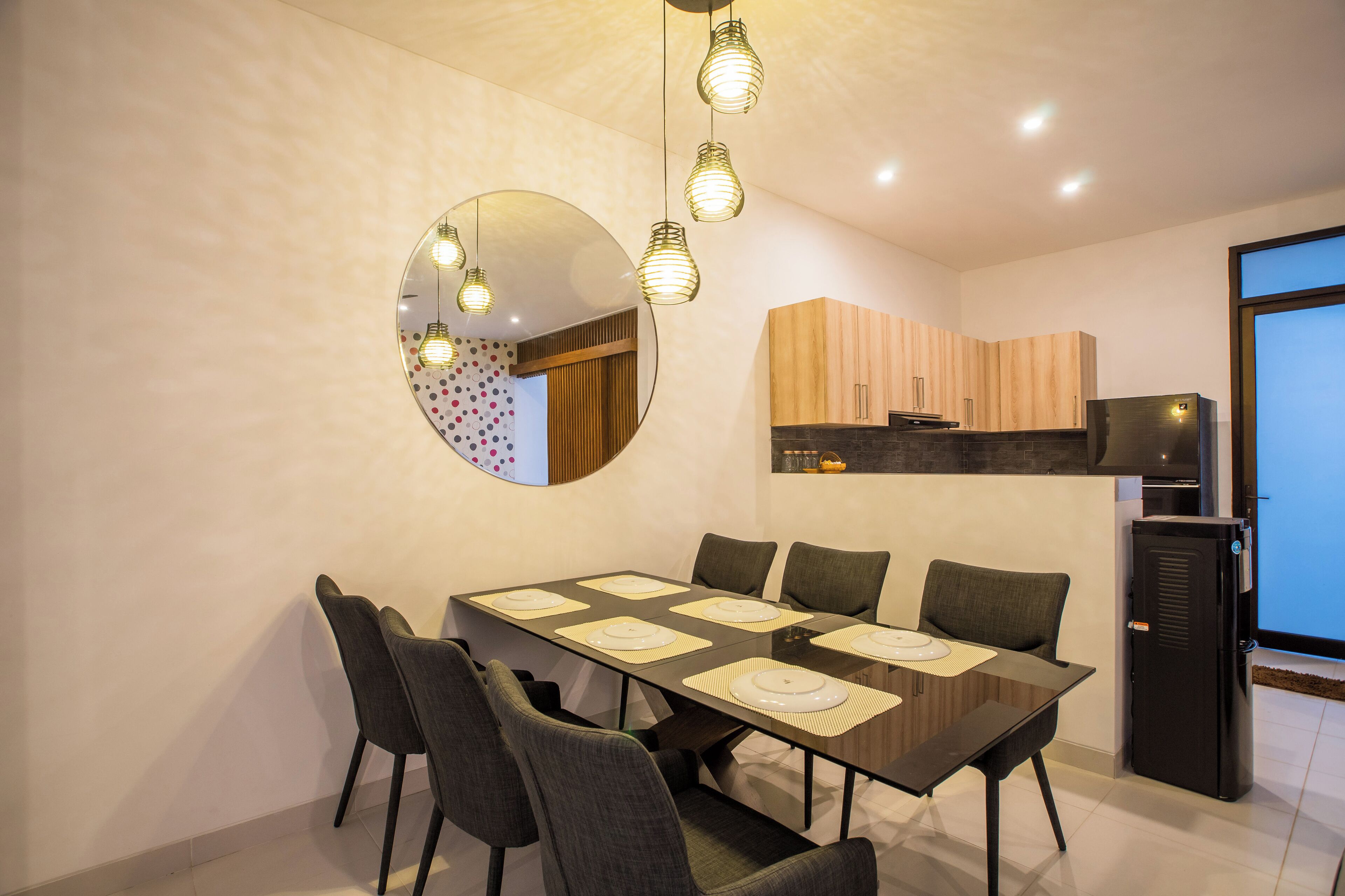 A modern dining area with a rectangular table, six chairs, and a large mirror on the wall.