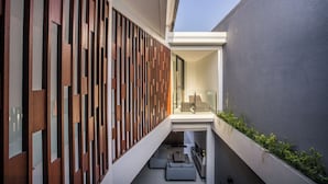 A modern interior with a wooden slatted wall, a seating area with sofas, and a small table. - Berawa Bali Beach Villa (Canggu)
