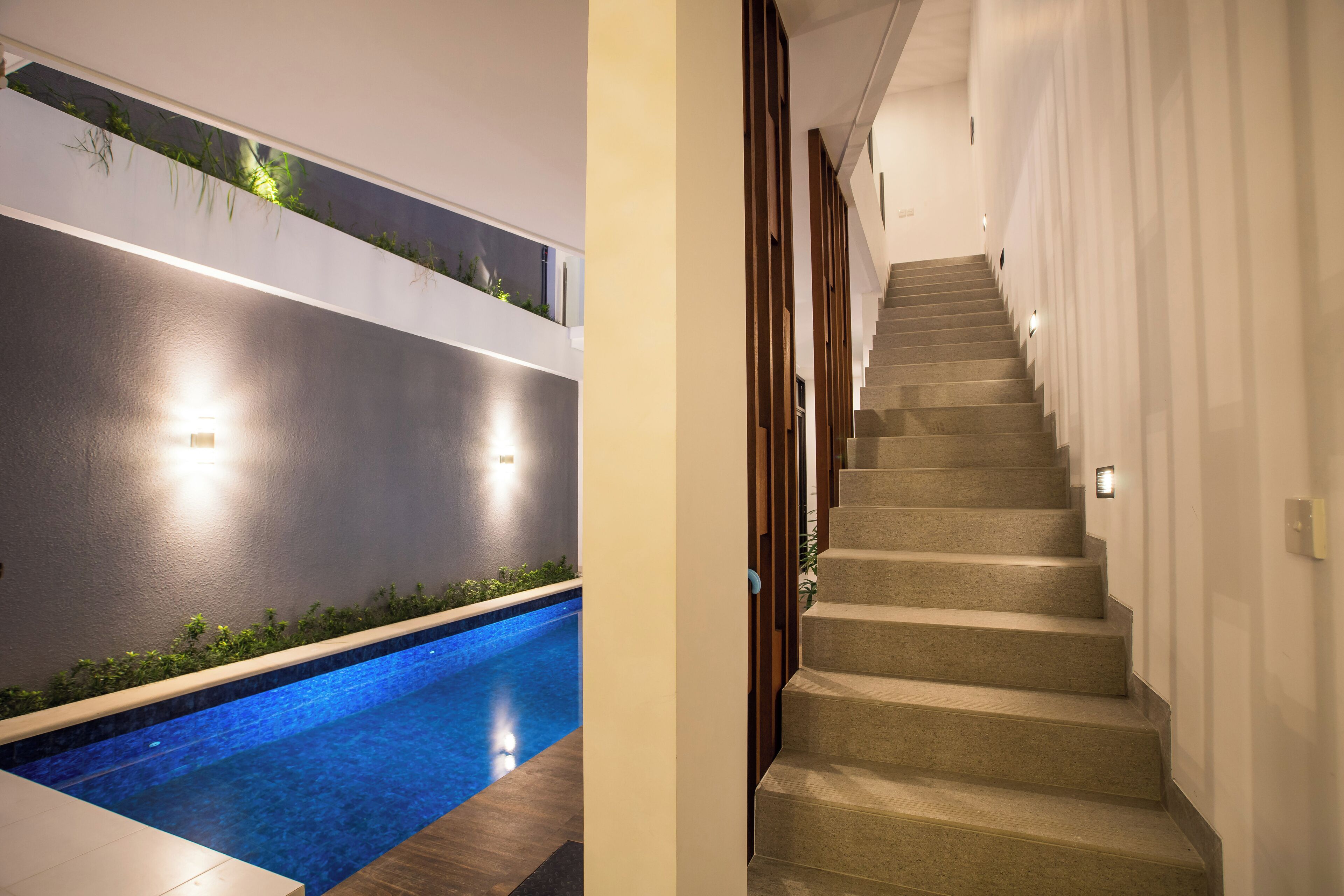 Un espace piscine intérieur moderne, avec un escalier menant à un niveau supérieur.