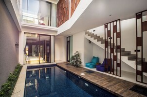 Um interior moderno com piscina, escada e área de estar com almofadas.