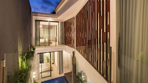 A modern residential building with a glass balcony, a pool, and a wooden facade. - Berawa Bali Beach Villa (Canggu)