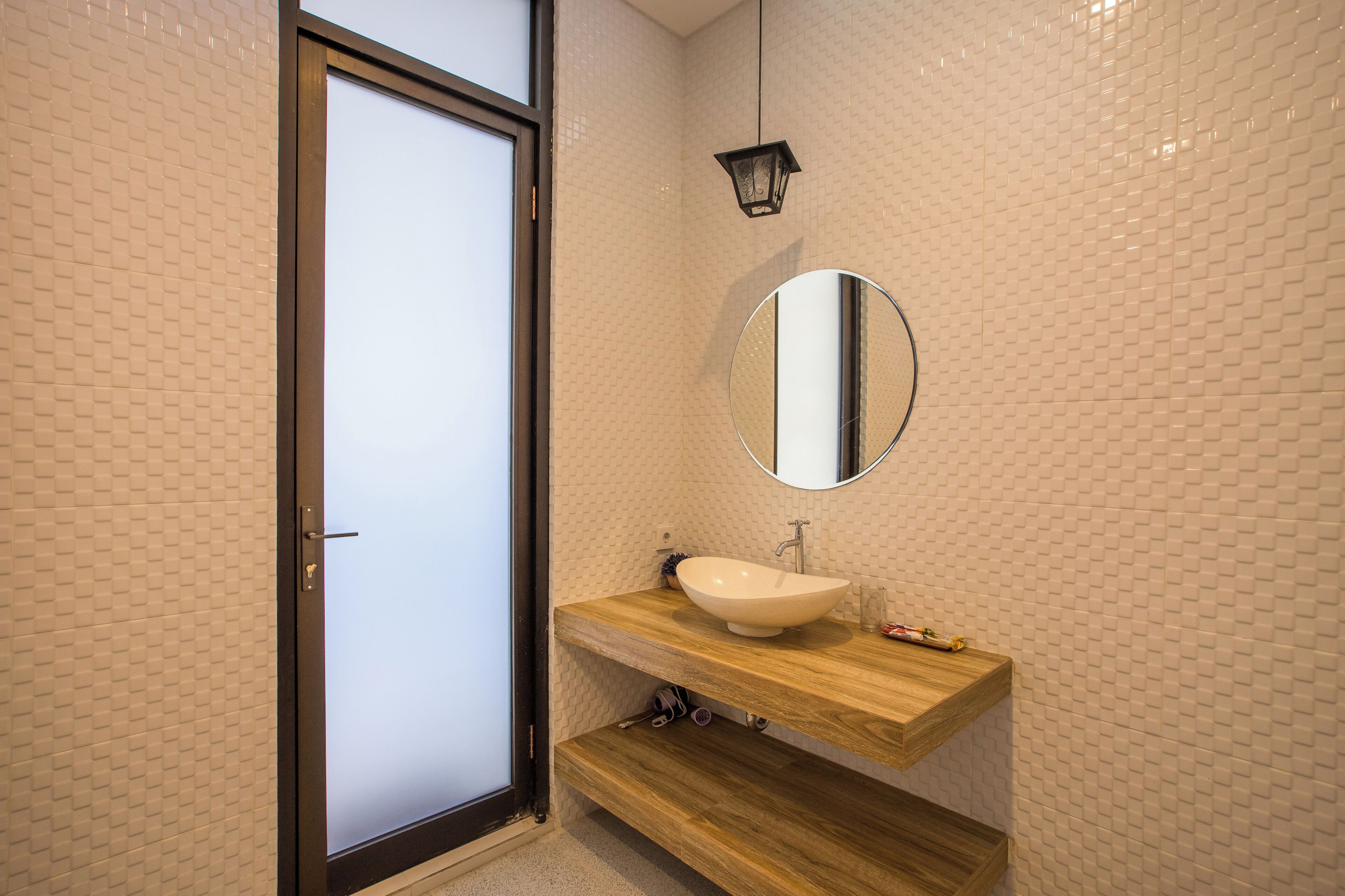Een badkamer met een houten wastafel, een witte wasbak en een spiegel.
