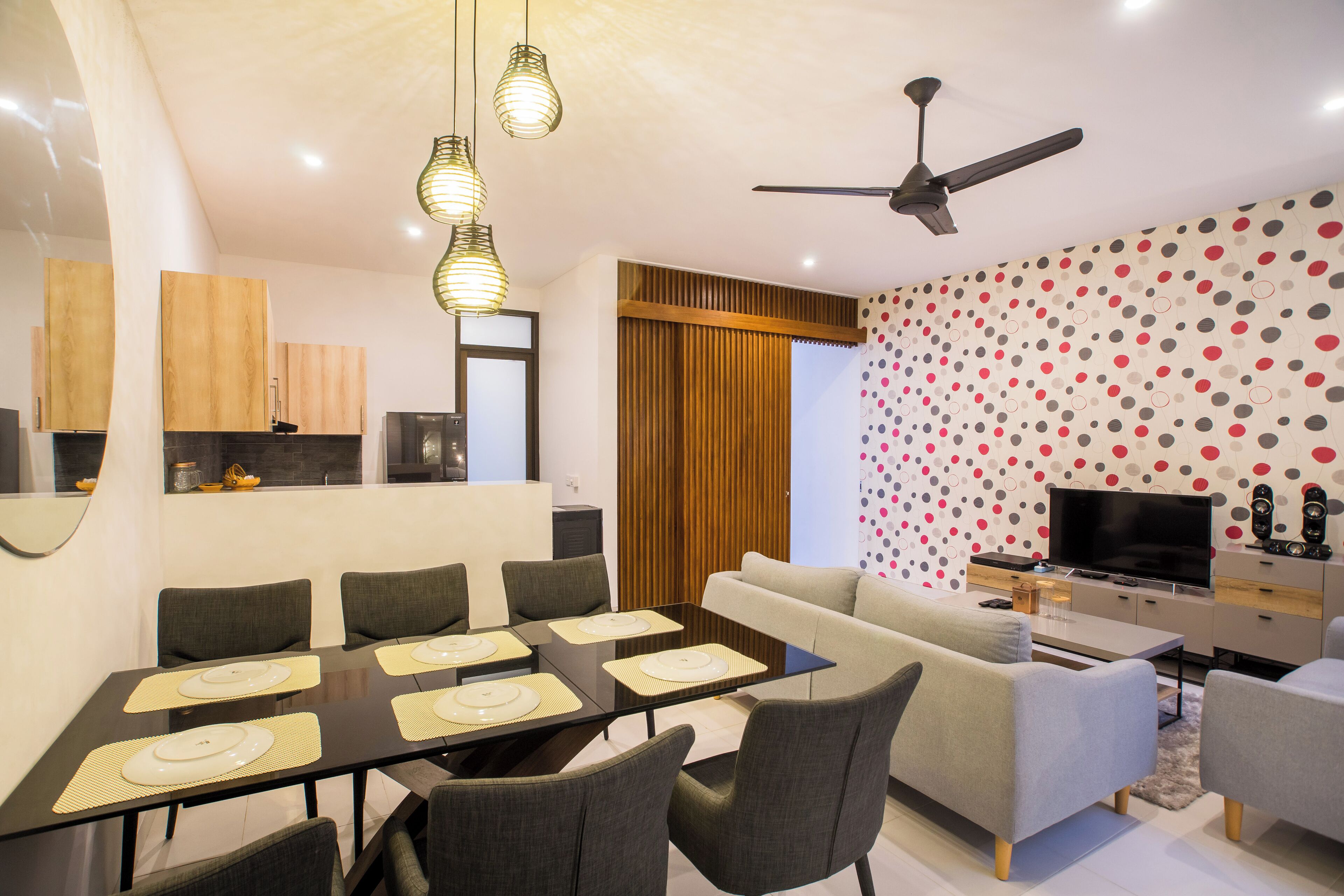 A modern living room with a dining area, a television, and a ceiling fan.