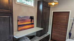 A hallway with dark wooden cabinets, a white shelf with a painting, and a wooden door. - Family-Friendly Private Ranch Getaway with pond. Newly Remodeled (Anaconda)