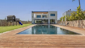A modern two-story house with a swimming pool, a wooden deck, and a slide. - Modern 4 bedroom villa with pool and barbecue (Llubi)