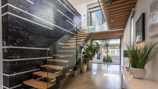 A modern staircase with glass railings, wooden steps, and black marble walls. - Modern 4 bedroom villa with pool and barbecue (Llubi)